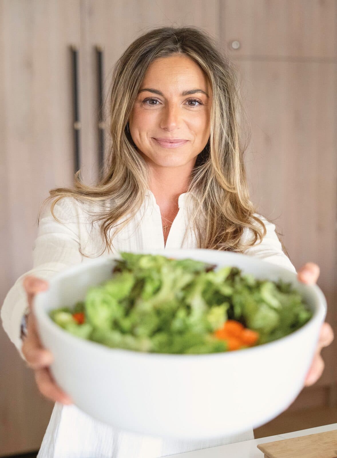 Danielle holding a big bowl of fresh salad out toward the camera